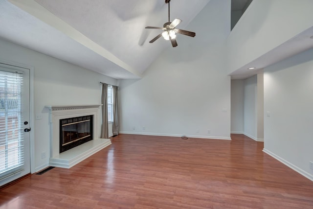 unfurnished living room featuring wood-type flooring, high vaulted ceiling, and ceiling fan