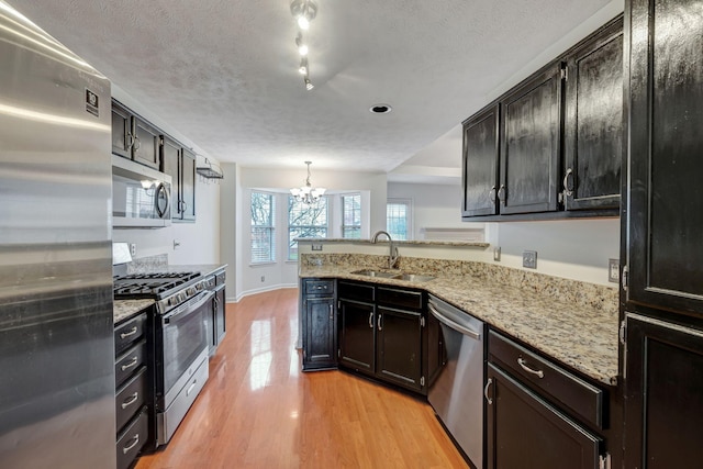 kitchen with sink, stainless steel appliances, an inviting chandelier, light hardwood / wood-style flooring, and pendant lighting