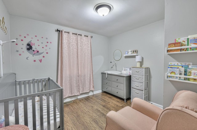 bedroom with dark hardwood / wood-style floors and a crib