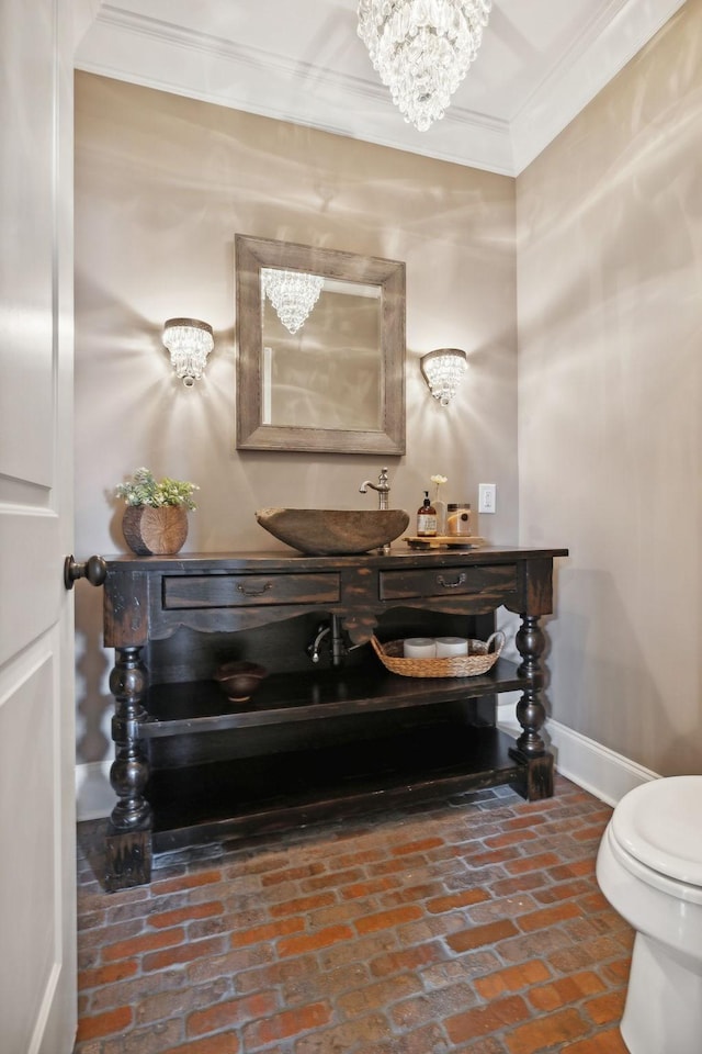 bathroom featuring crown molding, an inviting chandelier, vanity, and toilet