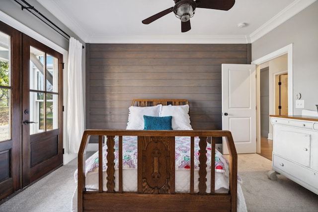 bedroom featuring ceiling fan, french doors, crown molding, wood walls, and light colored carpet