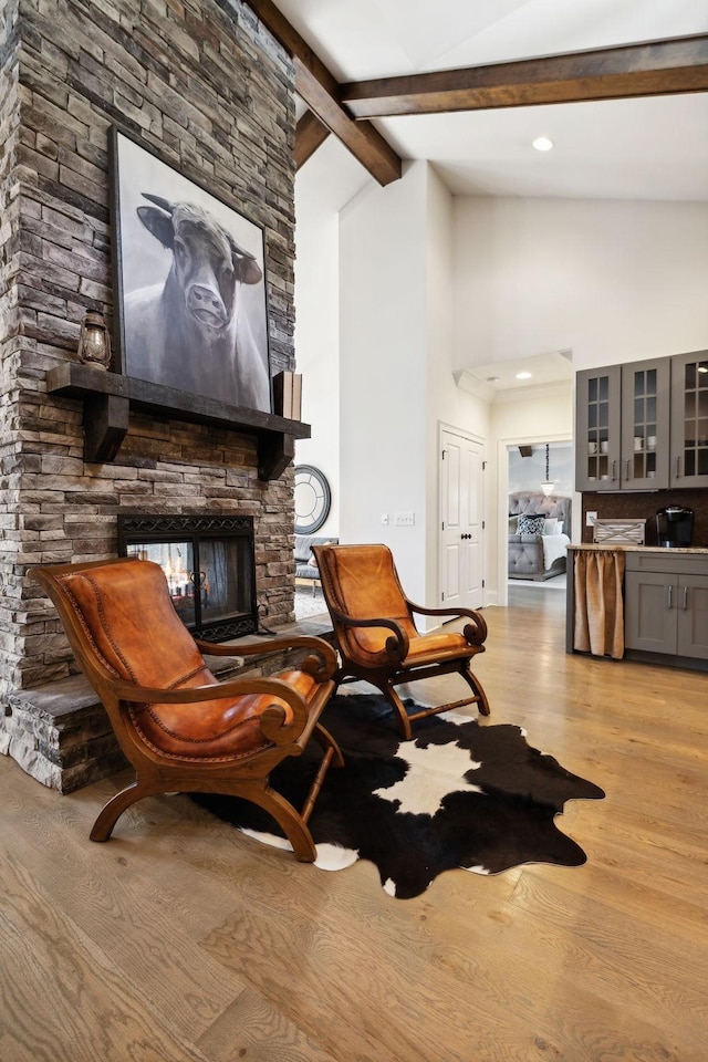 living area featuring vaulted ceiling with beams, light wood-type flooring, and a fireplace