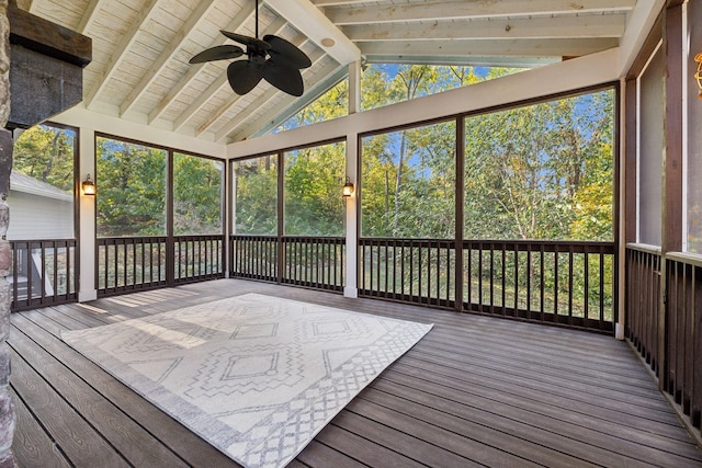 unfurnished sunroom featuring vaulted ceiling with beams, ceiling fan, and a healthy amount of sunlight