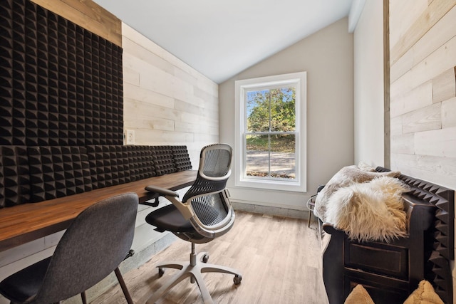 office space with wood walls, a healthy amount of sunlight, and vaulted ceiling