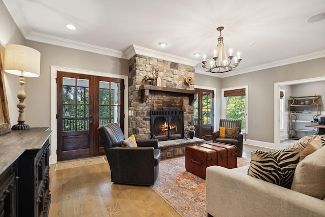 living room featuring a fireplace, ornamental molding, light hardwood / wood-style floors, and a notable chandelier