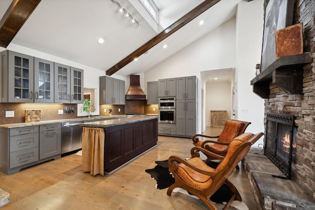 kitchen featuring decorative backsplash, appliances with stainless steel finishes, a center island, and premium range hood