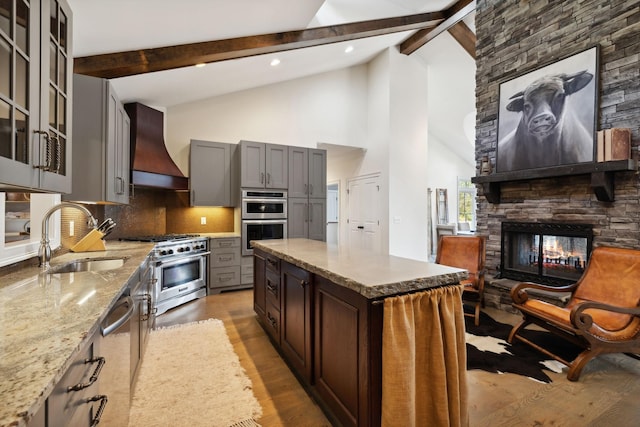 kitchen featuring sink, stainless steel appliances, beamed ceiling, backsplash, and custom range hood