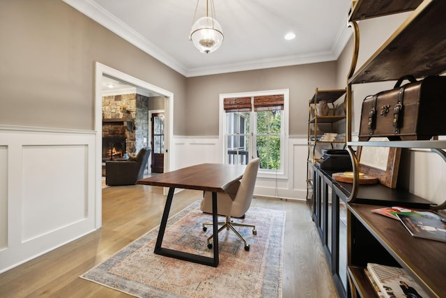 office area featuring light wood-type flooring, ornamental molding, and a fireplace