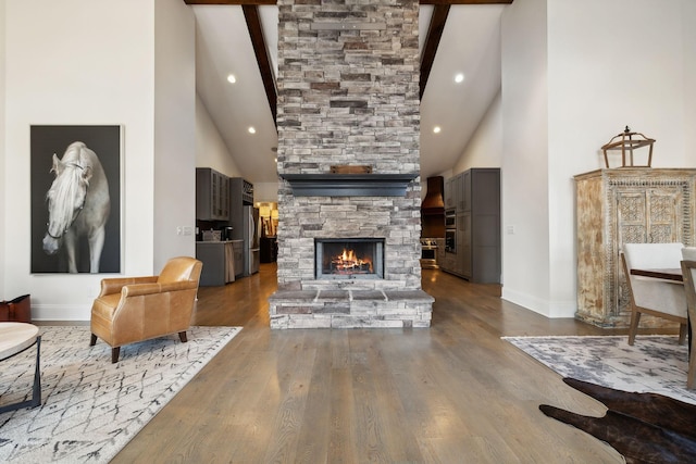 living room featuring beamed ceiling, dark hardwood / wood-style flooring, high vaulted ceiling, and a stone fireplace