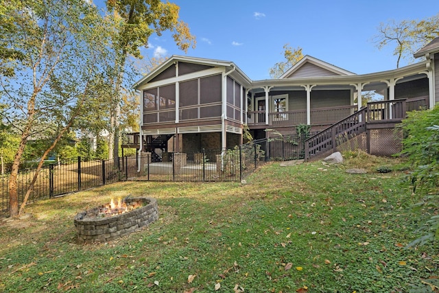 back of house with a fire pit, a sunroom, and a yard