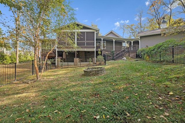 rear view of house featuring a fire pit, a sunroom, and a yard