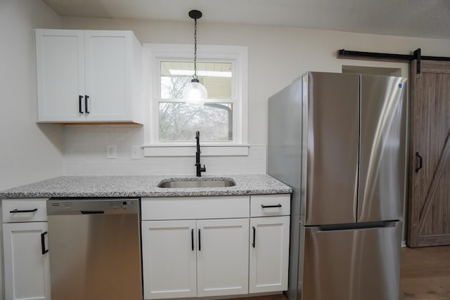 kitchen with white cabinets, a barn door, stainless steel appliances, and sink