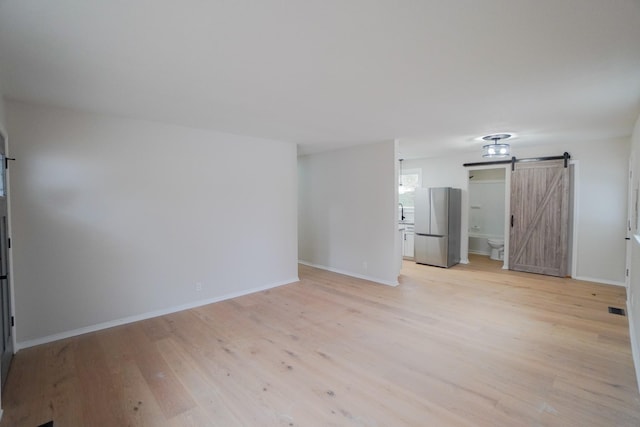 spare room featuring a barn door and light hardwood / wood-style floors