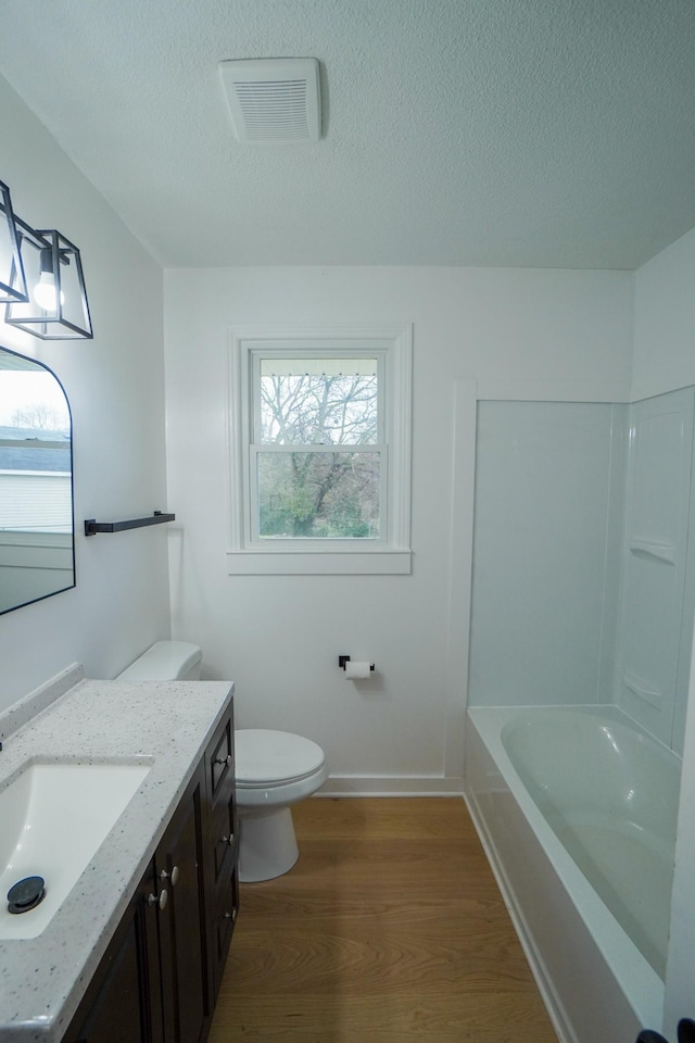 bathroom with hardwood / wood-style floors, vanity, a textured ceiling, and toilet