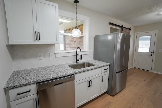 kitchen with light stone countertops, appliances with stainless steel finishes, tasteful backsplash, sink, and white cabinetry