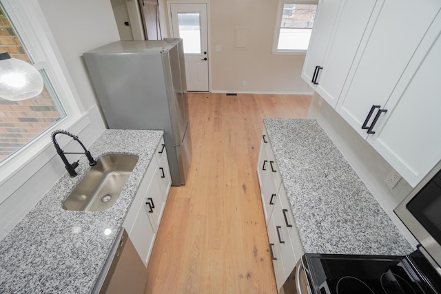 kitchen featuring white cabinets, light hardwood / wood-style flooring, and light stone counters