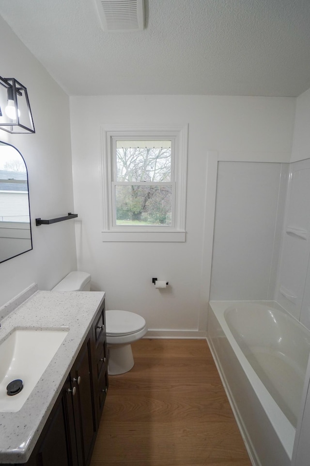 bathroom with wood-type flooring, vanity, a textured ceiling, and toilet