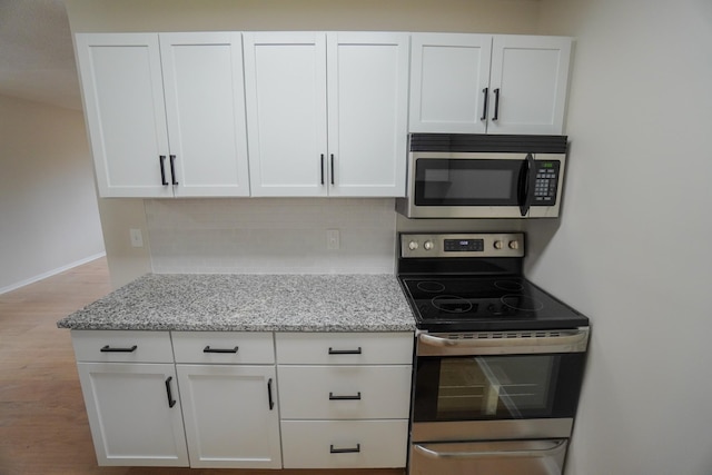 kitchen with decorative backsplash, light stone counters, white cabinets, and appliances with stainless steel finishes