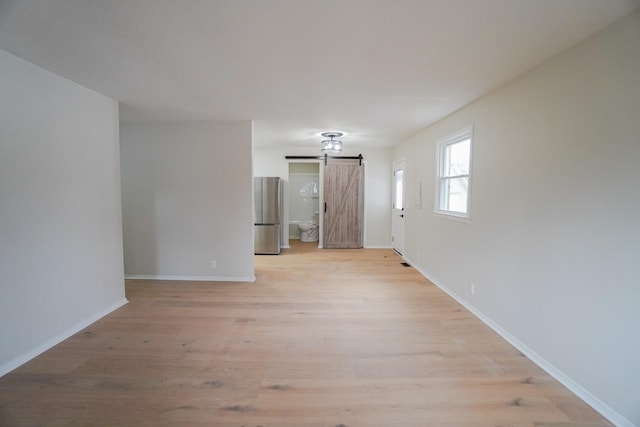 empty room featuring a barn door and light wood-type flooring