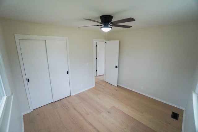 unfurnished bedroom featuring ceiling fan, a closet, and light wood-type flooring