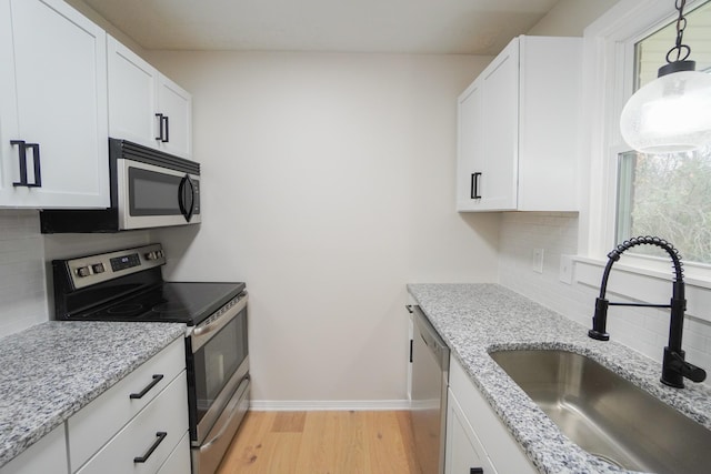 kitchen with decorative backsplash, stainless steel appliances, white cabinetry, and sink