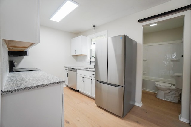 kitchen with sink, light hardwood / wood-style flooring, decorative light fixtures, white cabinetry, and stainless steel appliances