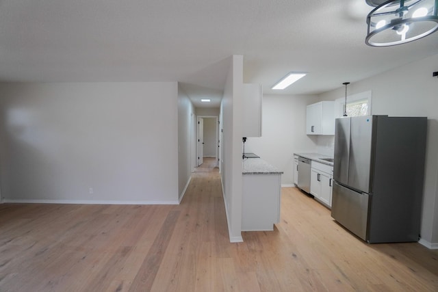 kitchen with pendant lighting, stainless steel appliances, white cabinetry, and light hardwood / wood-style floors