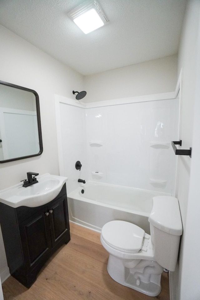 full bathroom with hardwood / wood-style floors,  shower combination, a textured ceiling, toilet, and vanity