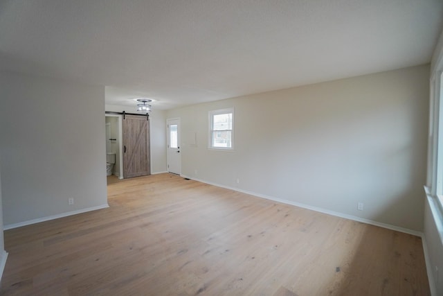 empty room featuring a barn door and light wood-type flooring