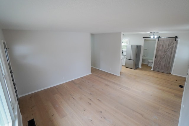 spare room with a barn door and light wood-type flooring