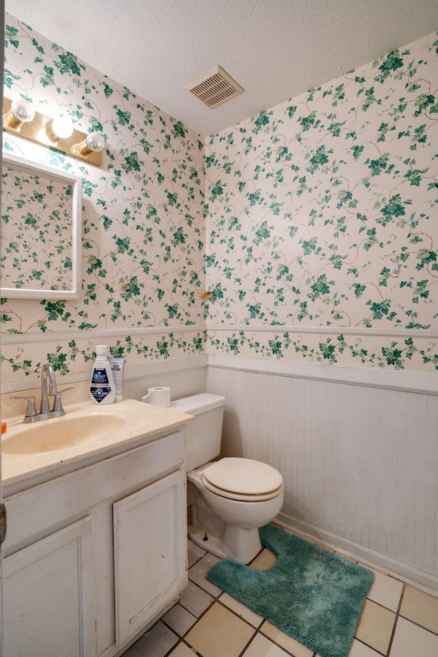 bathroom featuring a textured ceiling, toilet, tile patterned flooring, and vanity