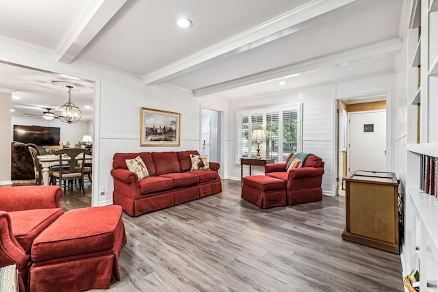 living room featuring beam ceiling, ceiling fan with notable chandelier, ornamental molding, and wood-type flooring