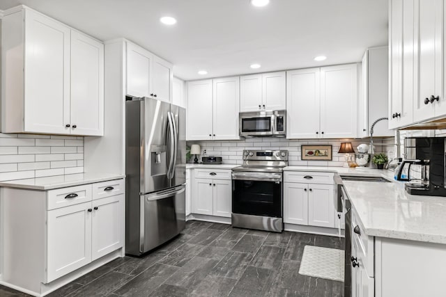 kitchen with backsplash, light stone countertops, white cabinetry, and stainless steel appliances