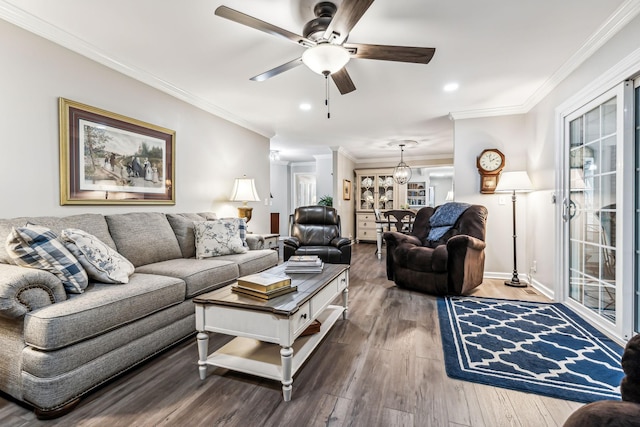 living room with hardwood / wood-style flooring, ceiling fan with notable chandelier, and crown molding