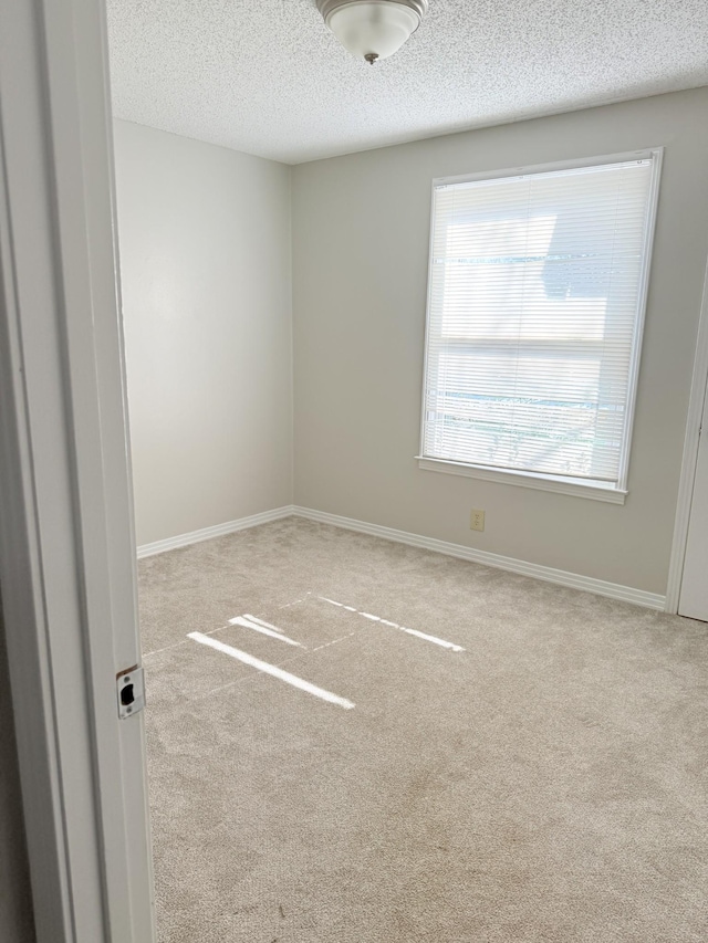 spare room with a textured ceiling and light carpet