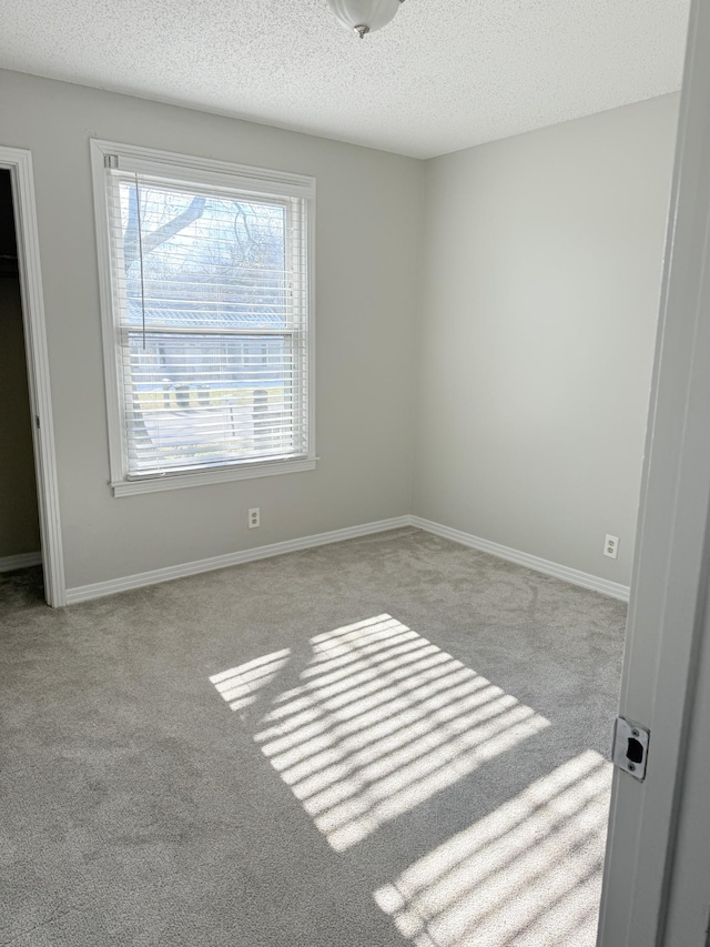 unfurnished room featuring a textured ceiling and light carpet