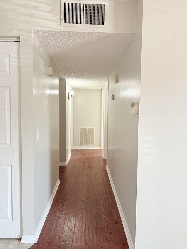 hallway with hardwood / wood-style flooring and a textured ceiling