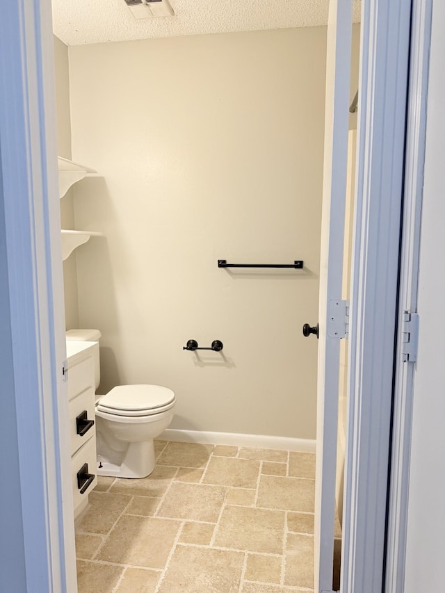 bathroom with toilet and a textured ceiling