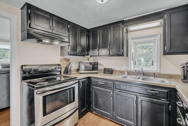 kitchen featuring sink, stainless steel appliances, a textured ceiling, and light hardwood / wood-style flooring