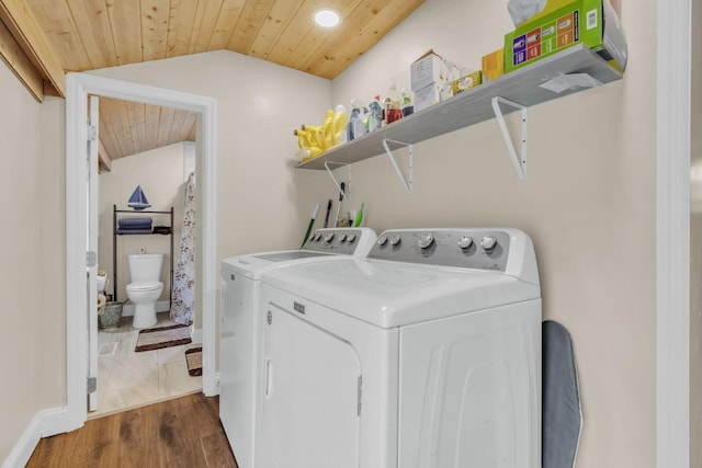 clothes washing area featuring dark hardwood / wood-style floors, washer and clothes dryer, and wooden ceiling