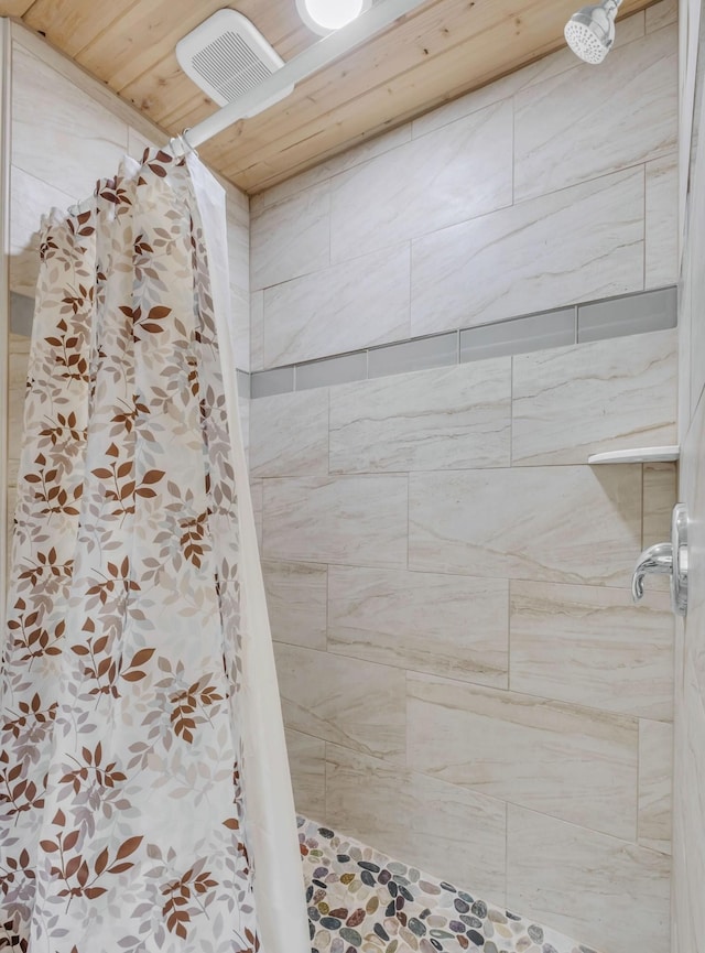 bathroom with a tile shower and wooden ceiling