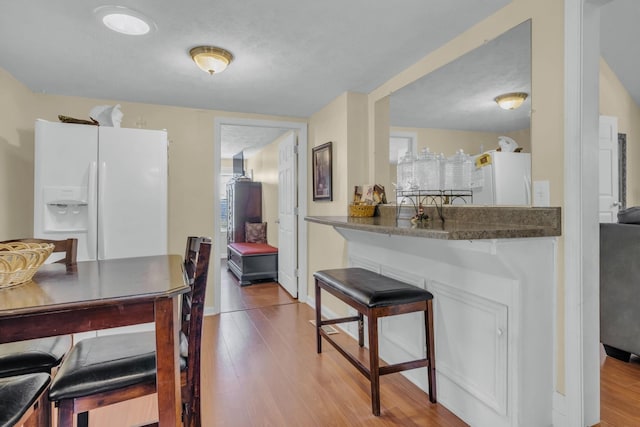 kitchen with white refrigerator, hardwood / wood-style flooring, and white fridge with ice dispenser