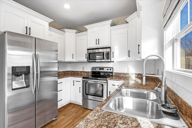 kitchen featuring white cabinetry, sink, light hardwood / wood-style floors, and appliances with stainless steel finishes