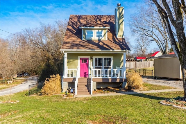 view of front of home featuring a front yard, a porch, and a storage shed