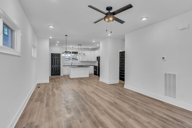 unfurnished living room with sink, ceiling fan, and light hardwood / wood-style flooring