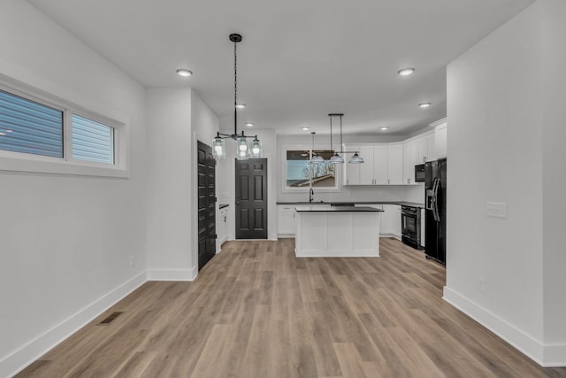 kitchen featuring black appliances, a kitchen island, white cabinets, pendant lighting, and backsplash