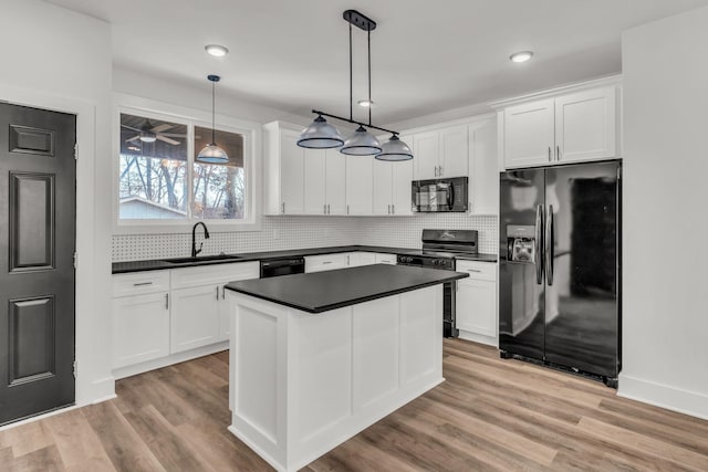 kitchen featuring white cabinets, sink, hanging light fixtures, and black appliances