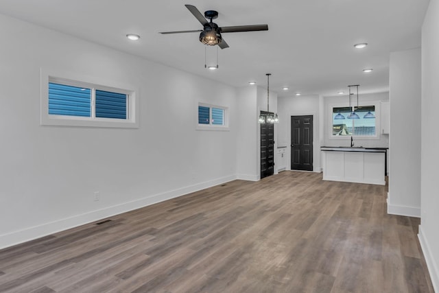 unfurnished living room featuring hardwood / wood-style flooring, ceiling fan, and sink