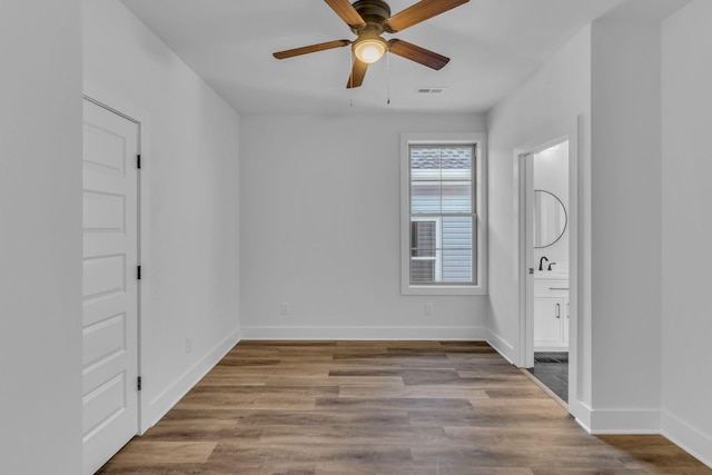 empty room with ceiling fan, sink, and light wood-type flooring