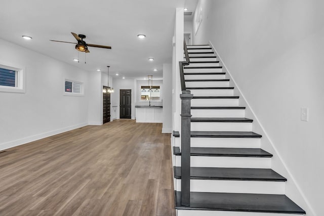 staircase with ceiling fan and hardwood / wood-style floors